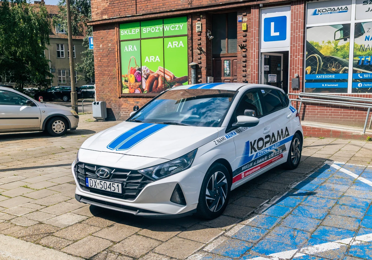 Biały Hyundai i20 z oznaczeniem samochodu szkoleniowego.
