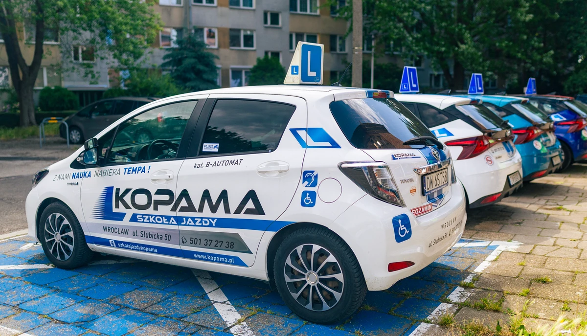 White Toyota Yaris Hybrid displaying learner-driver markings.